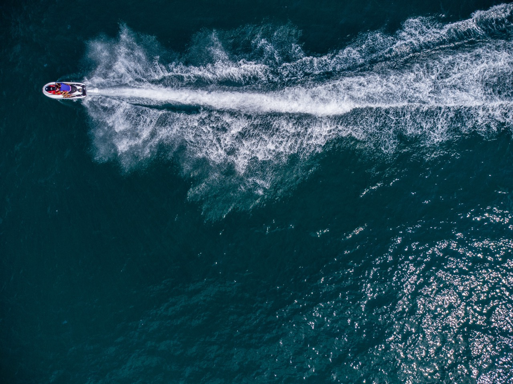 Groß (aerial-view-of-floating-scooter-on-blue-sea-at-sun-2023-11-27-05-31-00-utc).webp